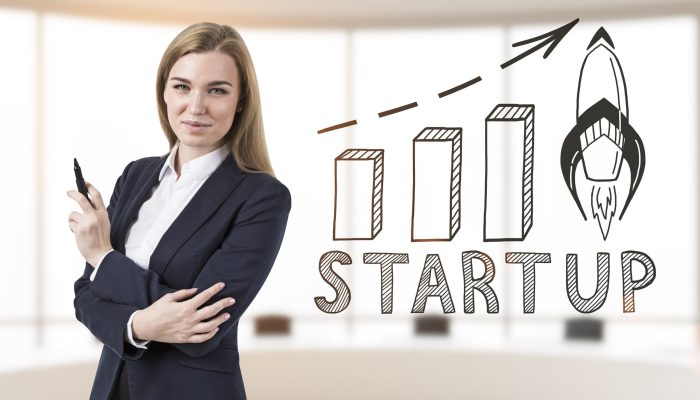 Businesswoman with marker and start up Portrait of a smiling blond businesswoman holding a black marker and standing in an office with a start up sketch and a growing graph. 3d rendering